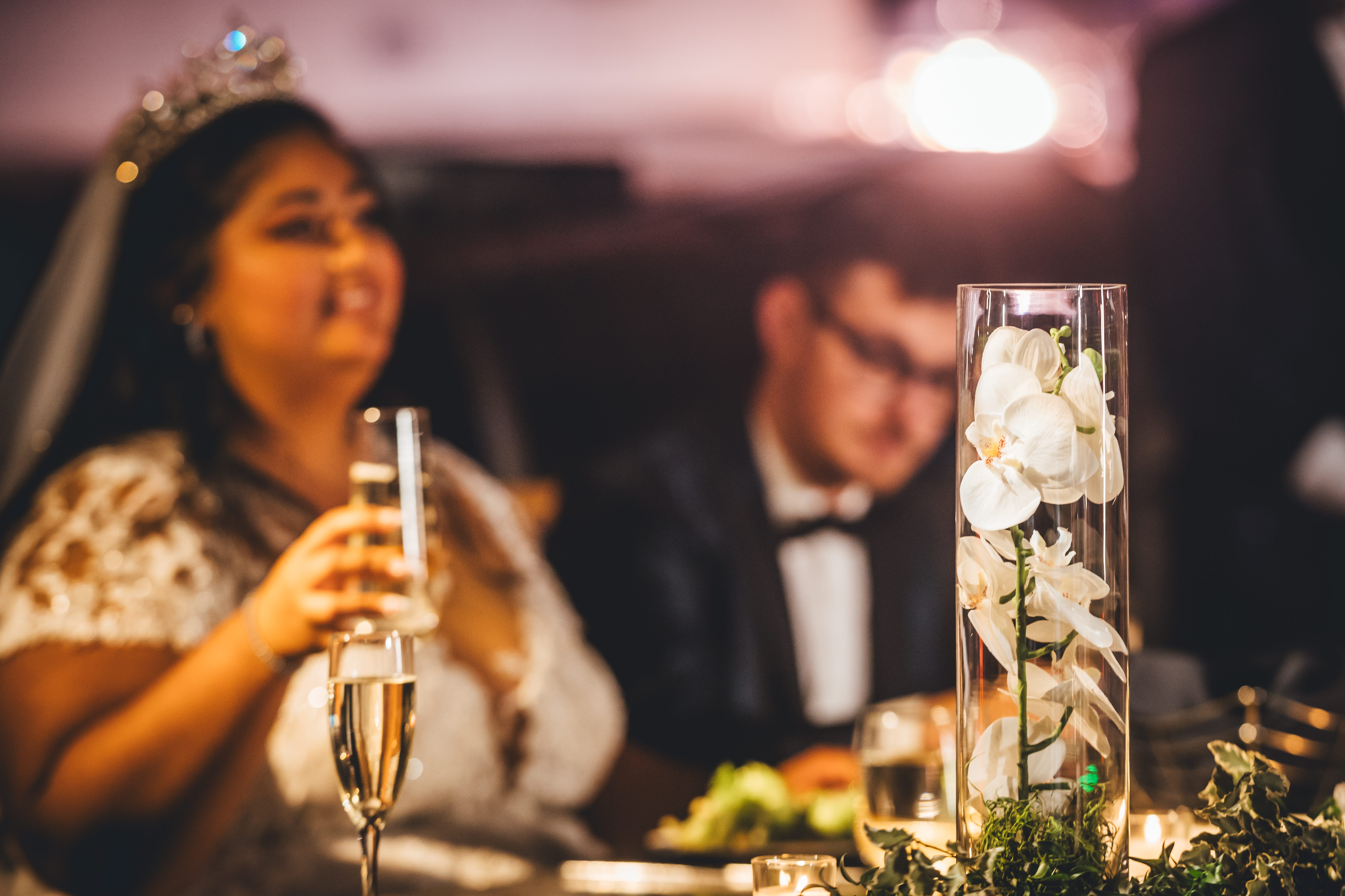 The bride raises a toast beside an orchid centerpiece at the reception table