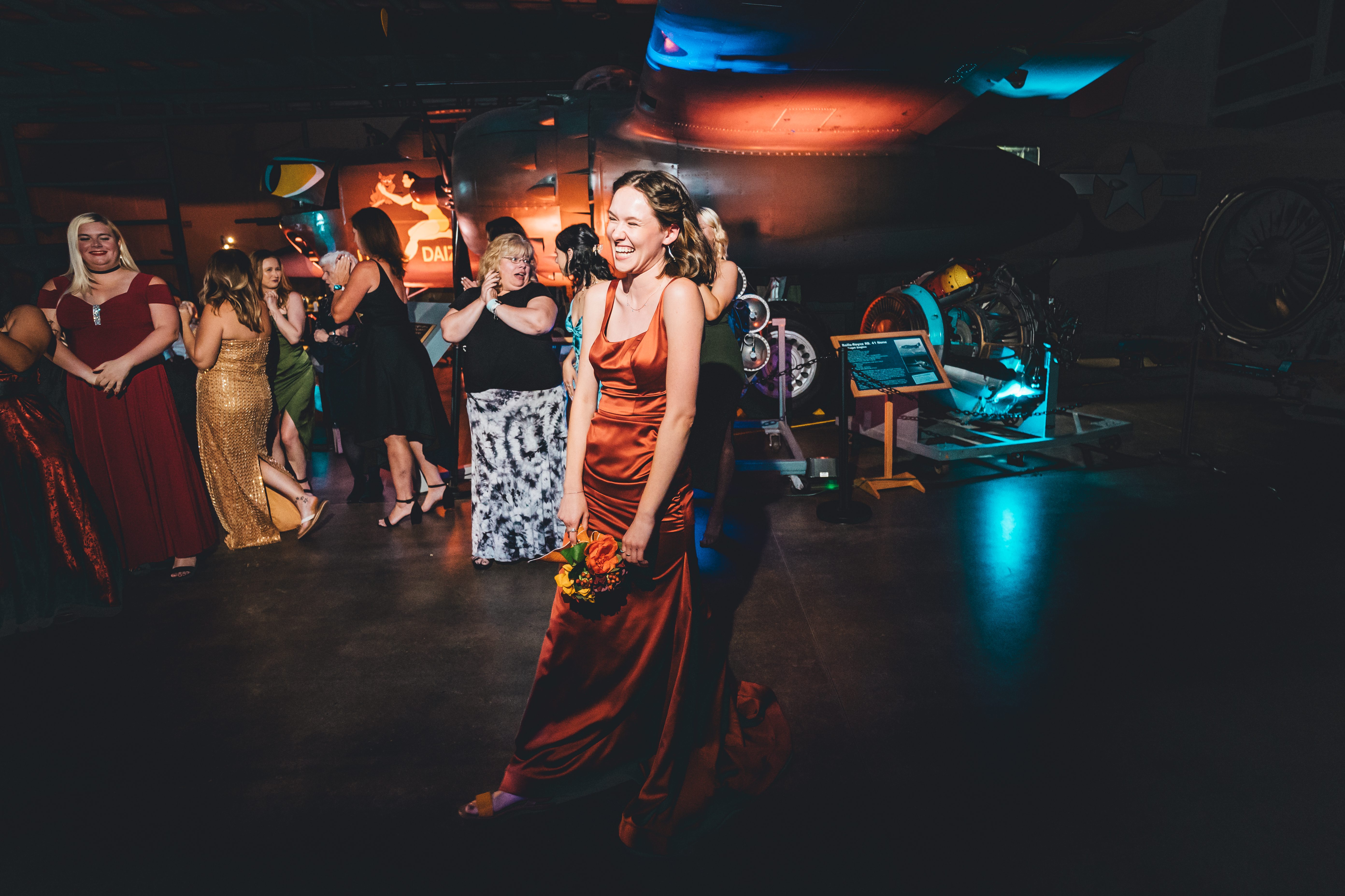 A guest laughing on the dance floor at an air museum wedding reception