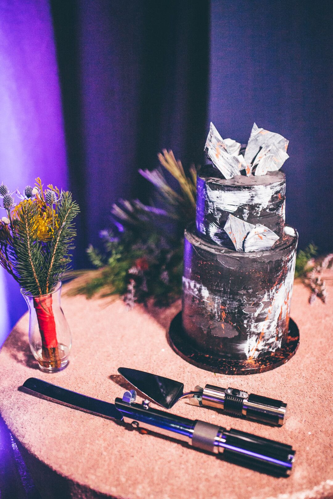 Black and silver galaxy wedding cake with lightsaber hilts beside it