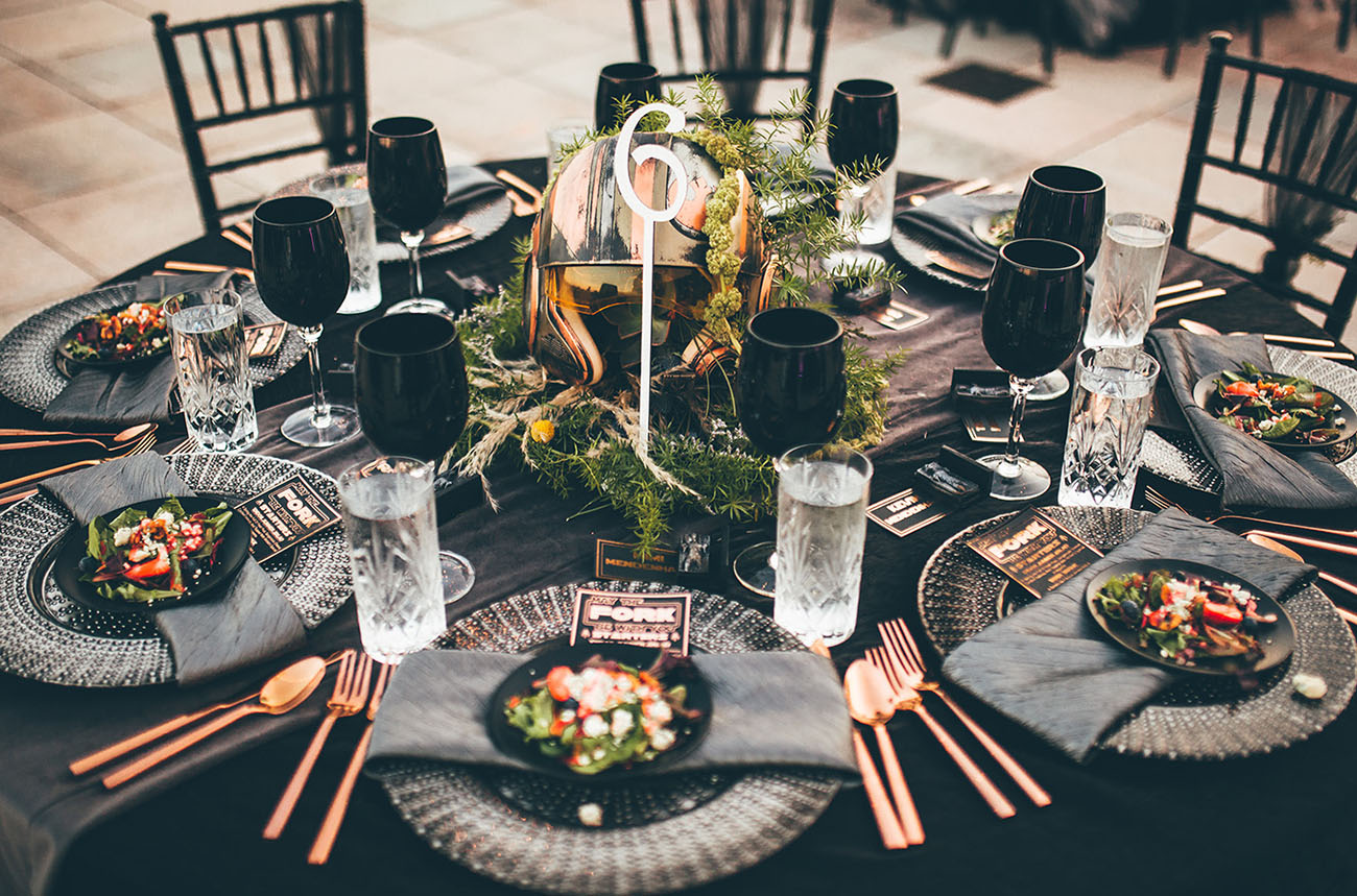 A Rebel pilot helmet centerpiece surrounded by greenery on a Star Wars wedding table