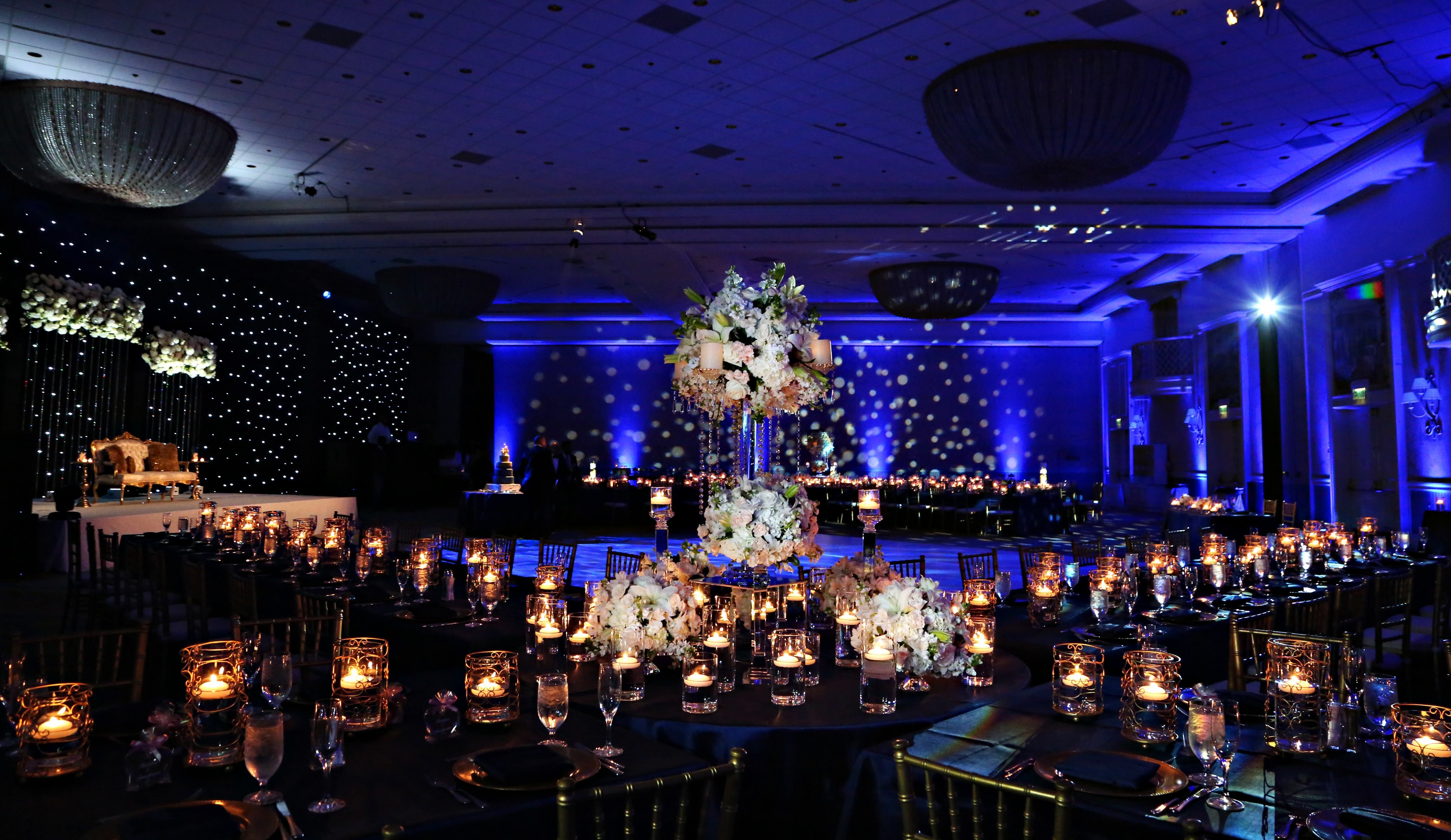 Ballroom reception with a star-lit backdrop, blue uplighting, and candlelit tables